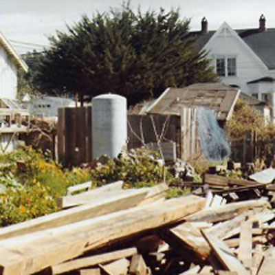 Garden area stacked with salvaged wood, Sea Gull Inn to the south
